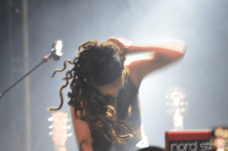 Natalli Rize playing a drum hair flying about her.