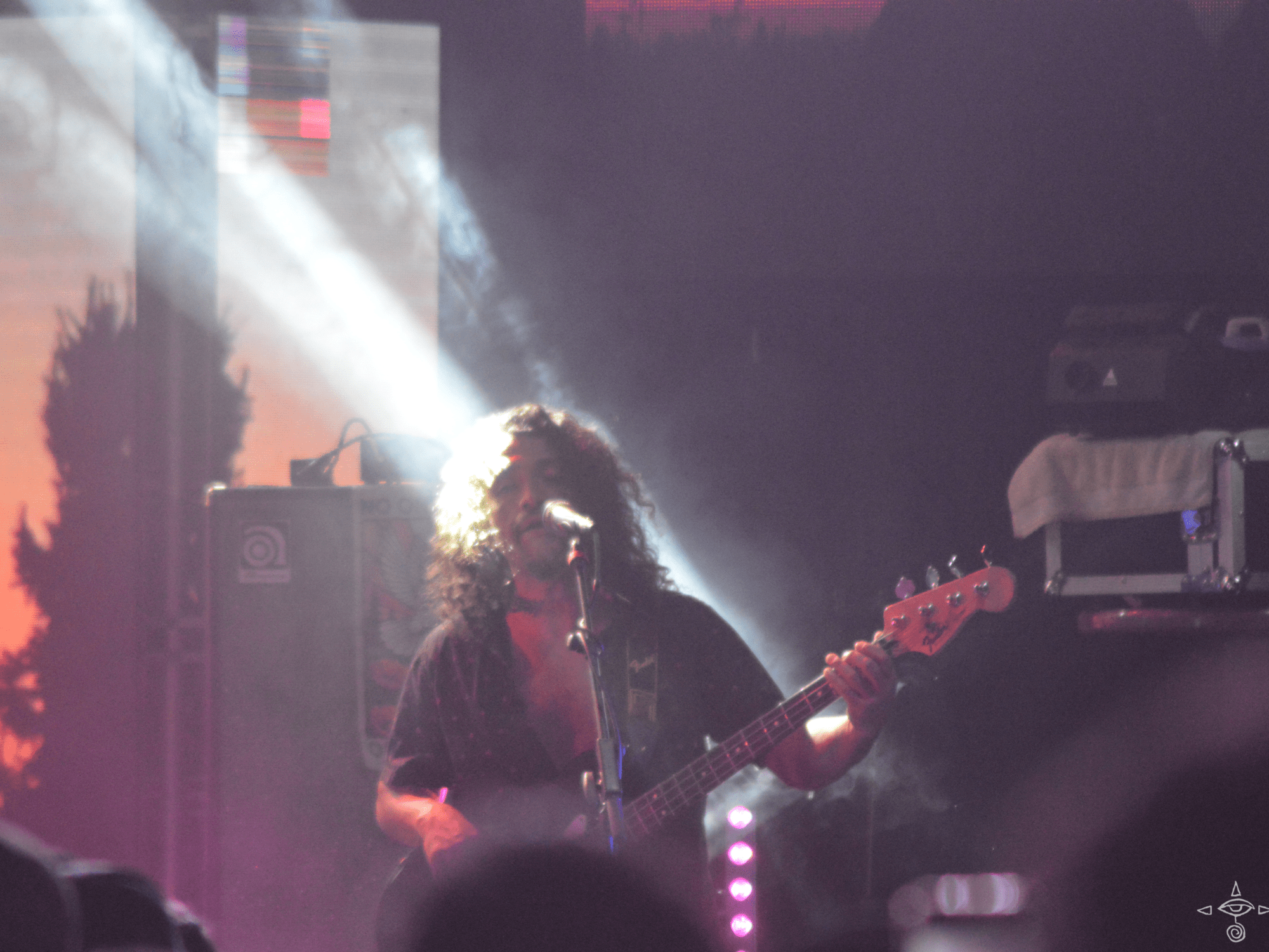 The bass player, Patricio Zuñiga Labarca, standing and playing the bass in a beam of light, A scanable code logo in the bottom right corner
