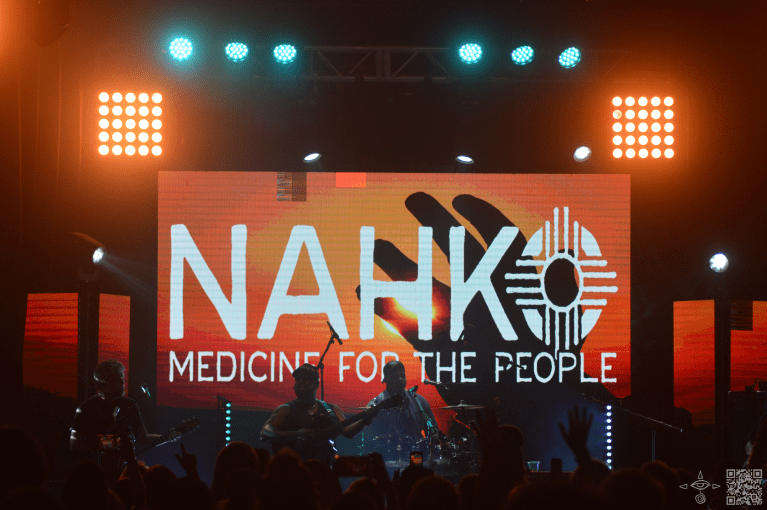 Nahko stage and band on stage, Whites and Oranges, A Hand in the Sun,. Big orange flood lights on the top corners of both sides.
